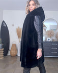 Manteau fausse fourrure noire à capuche sans manche.
