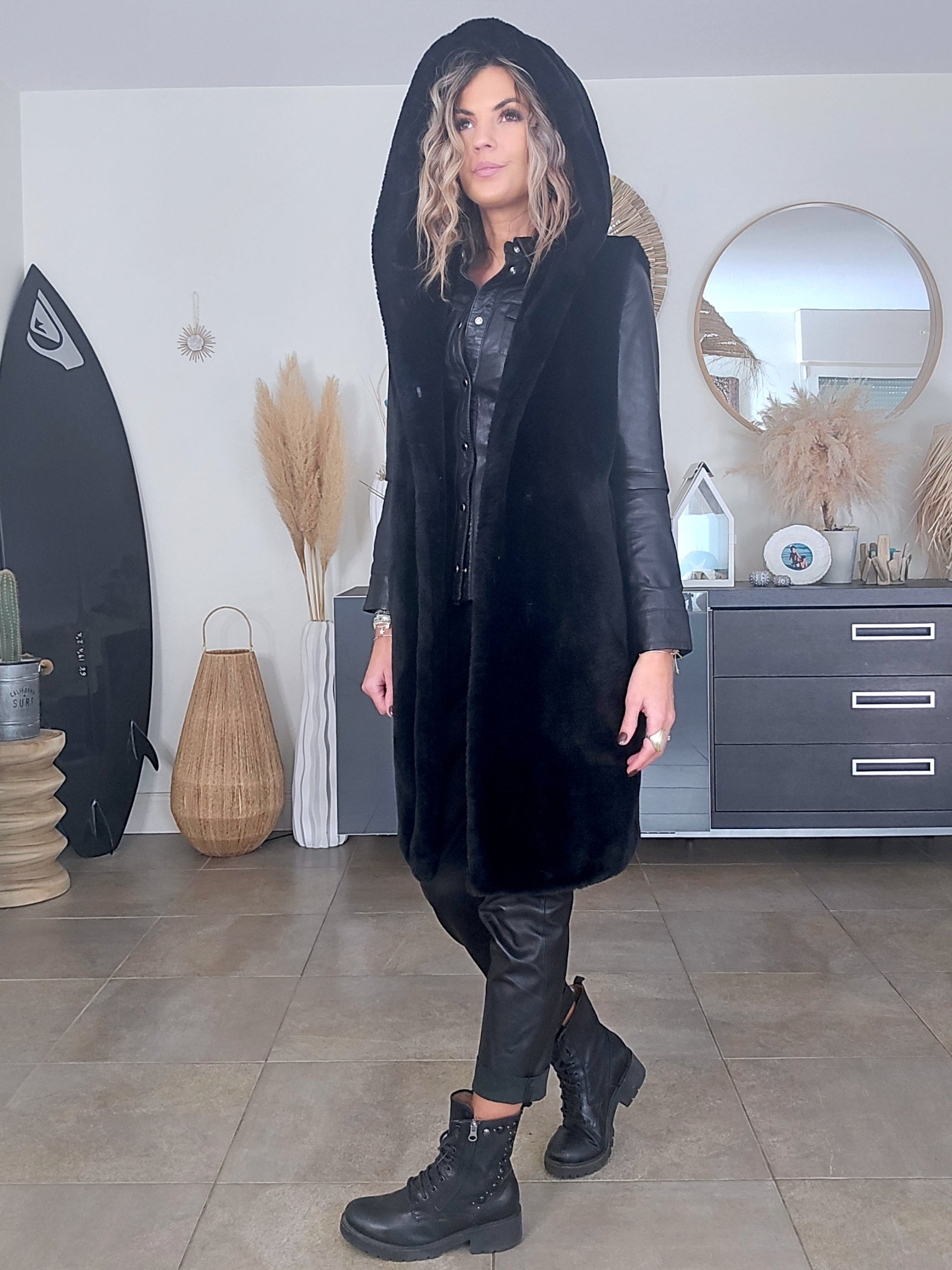 Manteau fausse fourrure noire à capuche sans manche.