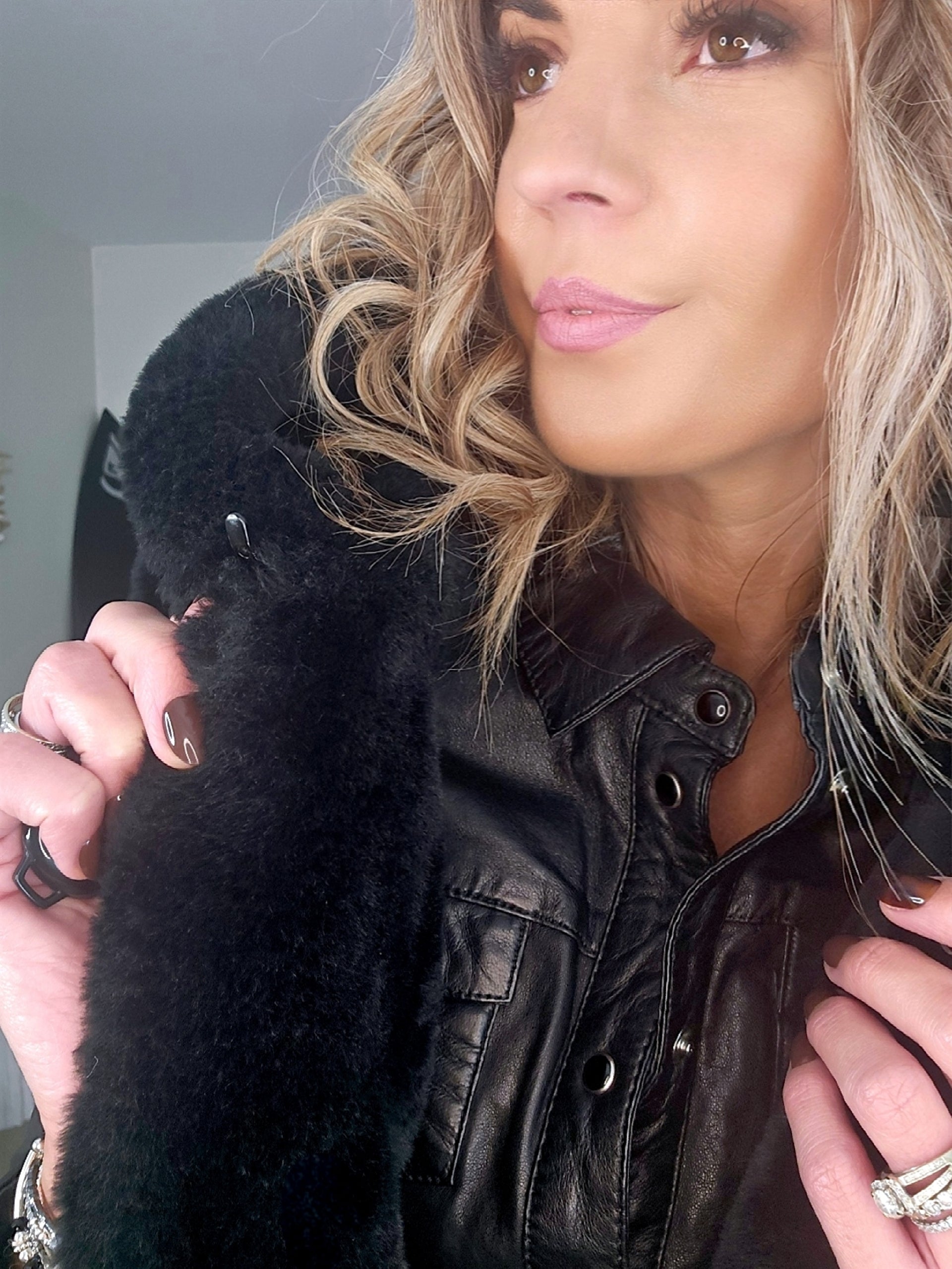 Manteau fausse fourrure noire à capuche sans manche.