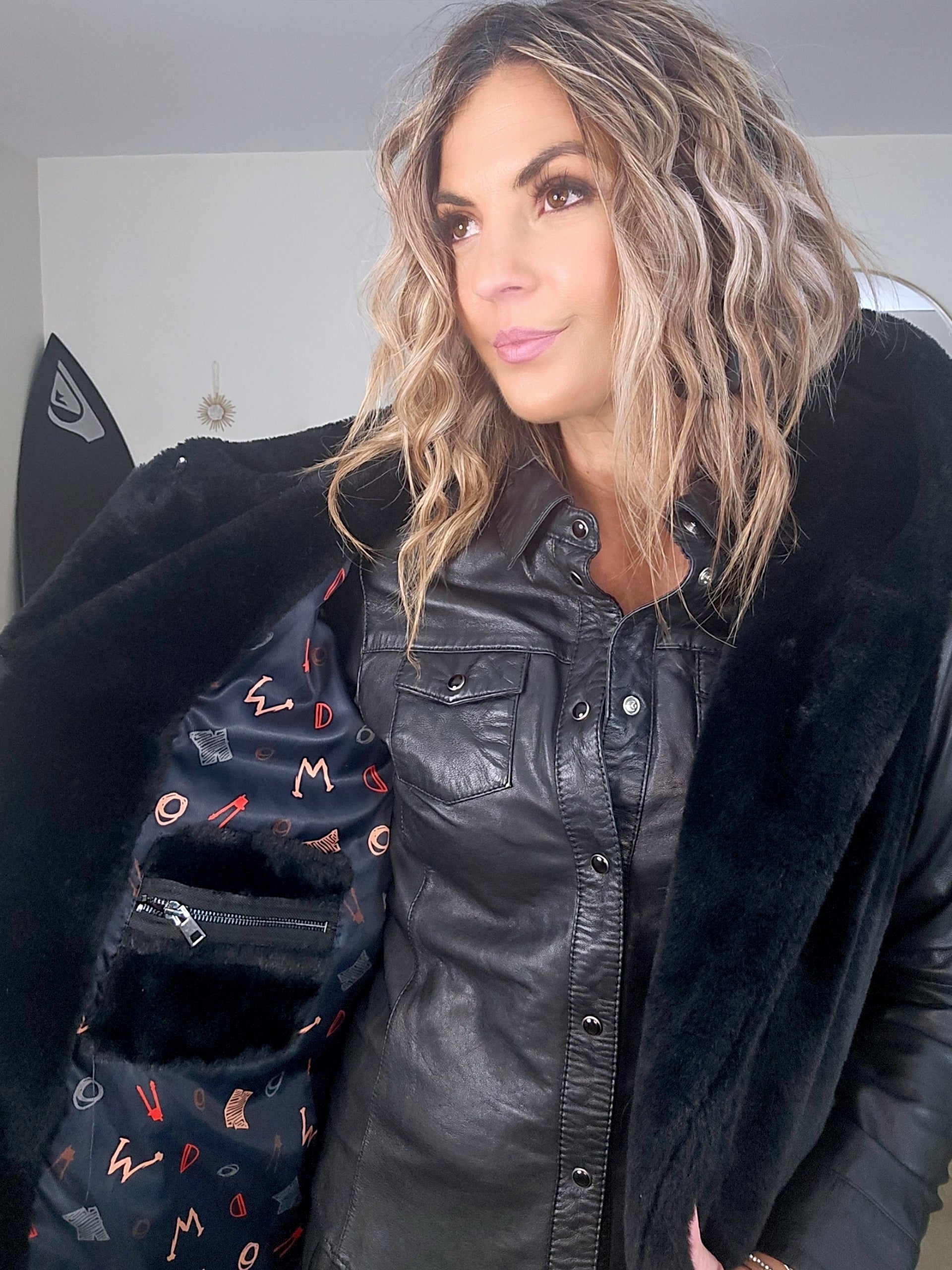 Manteau fausse fourrure noire à capuche sans manche.