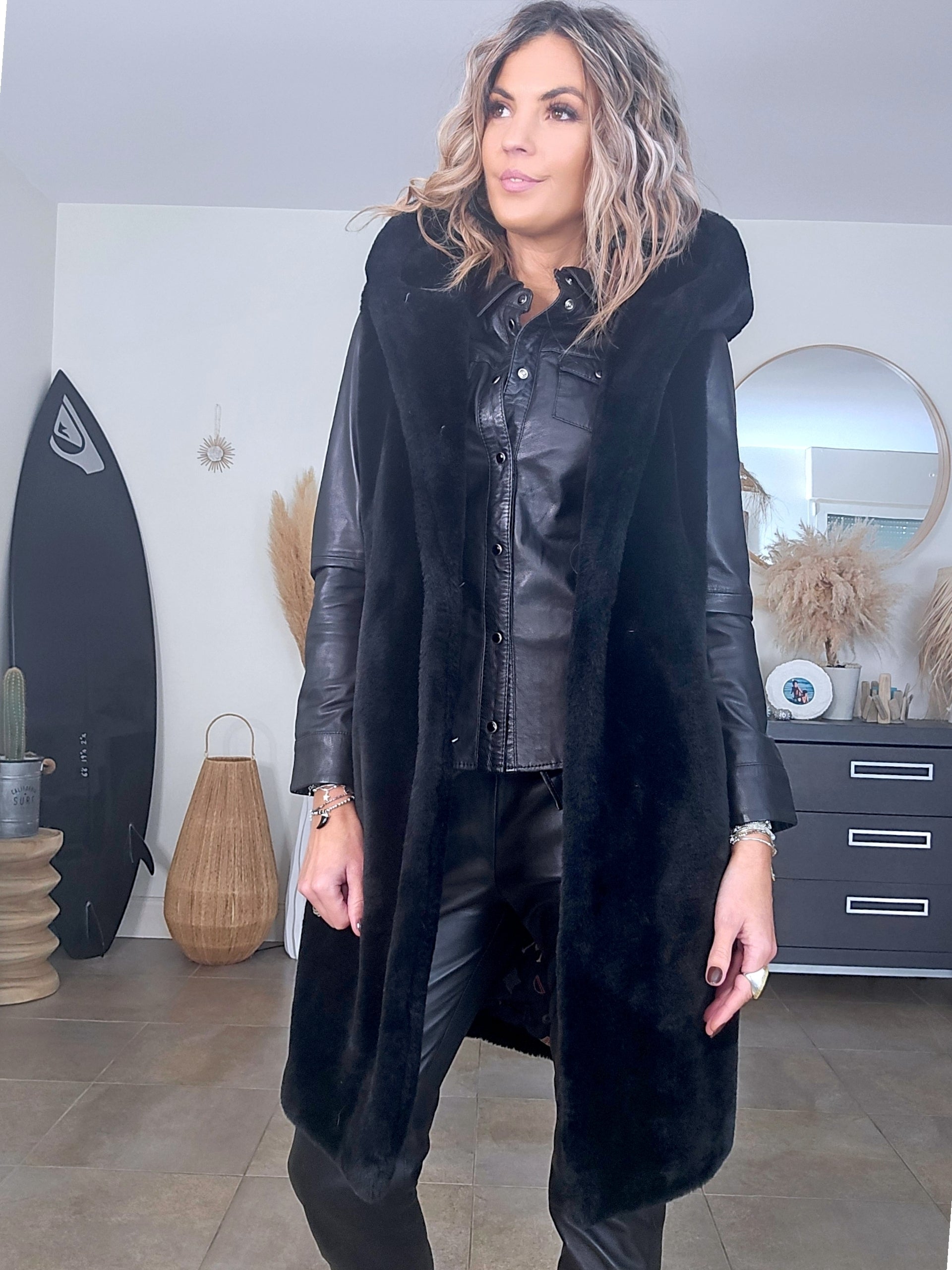 Manteau fausse fourrure noire à capuche sans manche.