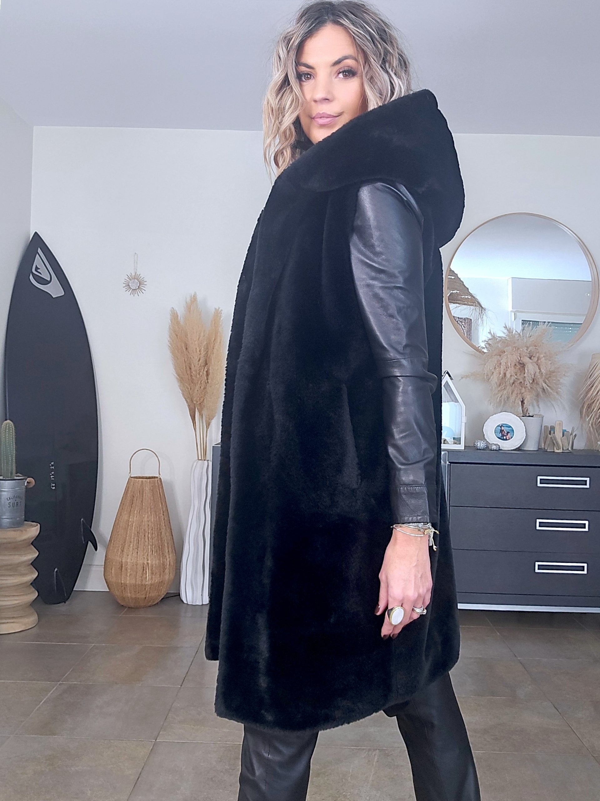 Manteau fausse fourrure noire à capuche sans manche.