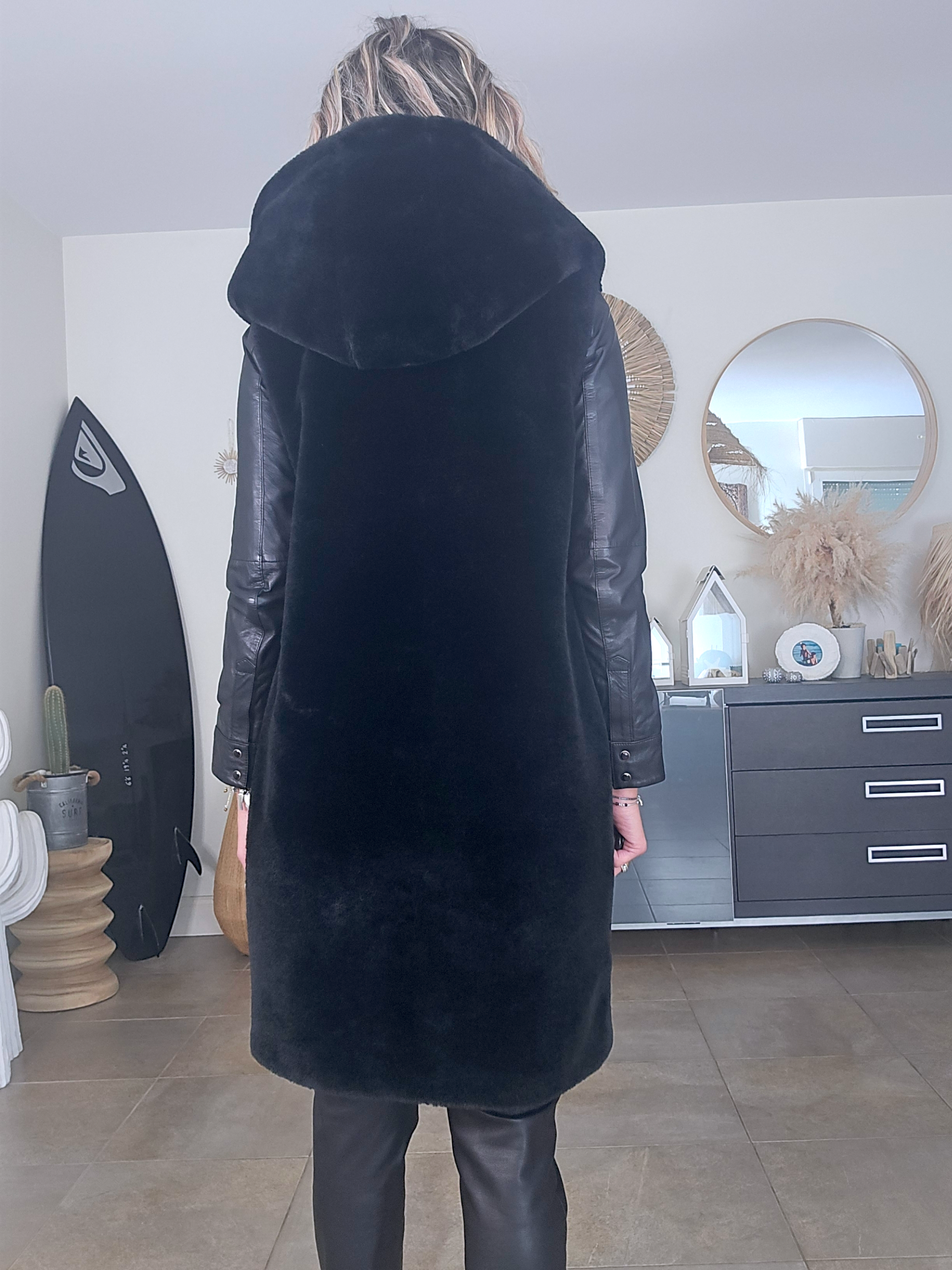 Manteau fausse fourrure noire à capuche sans manche.