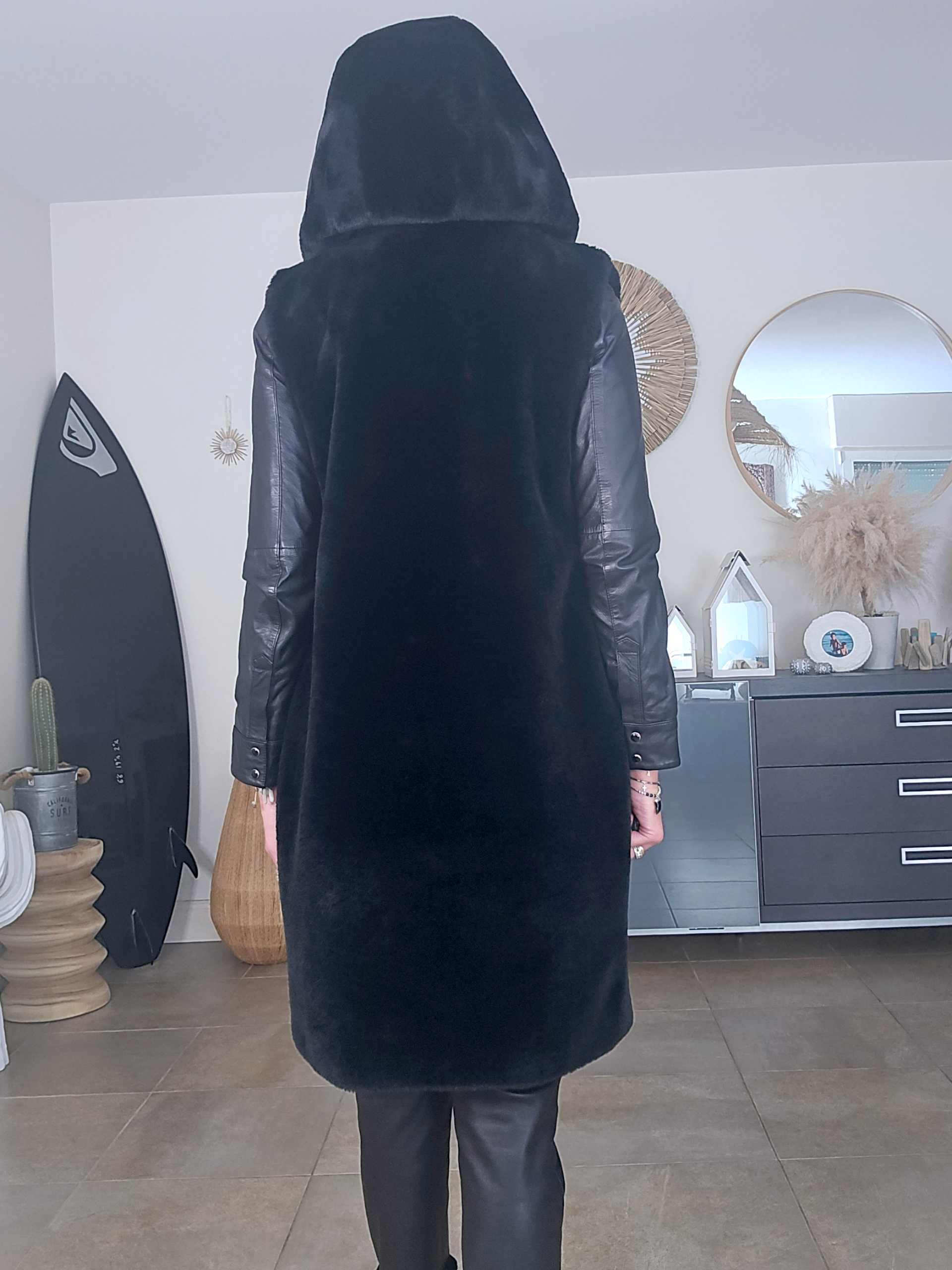 Manteau fausse fourrure noire à capuche sans manche.