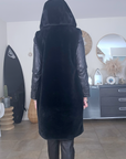 Manteau fausse fourrure noire à capuche sans manche.