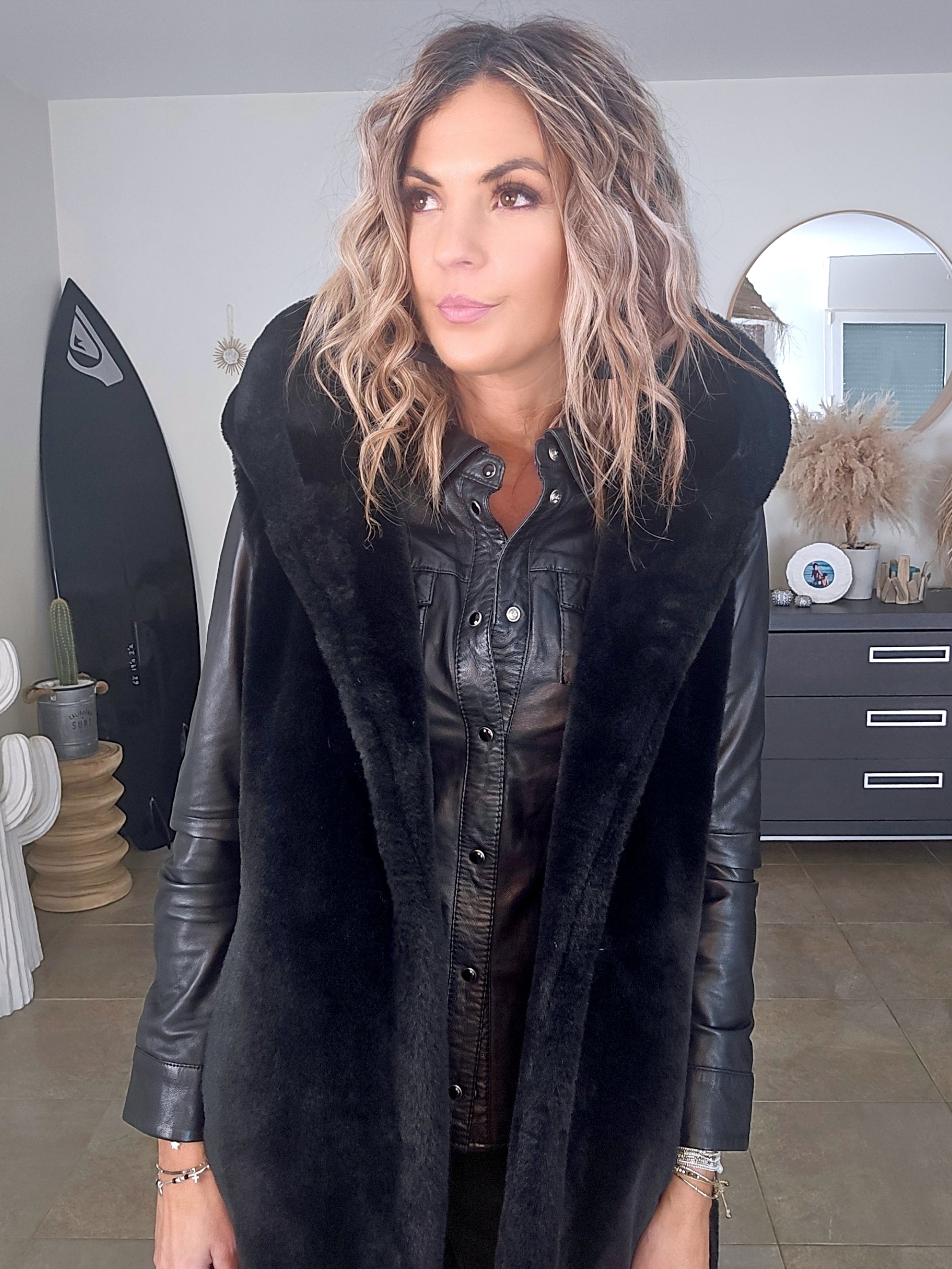 Manteau fausse fourrure noire à capuche sans manche.