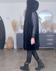 Manteau fausse fourrure noire à capuche sans manche.