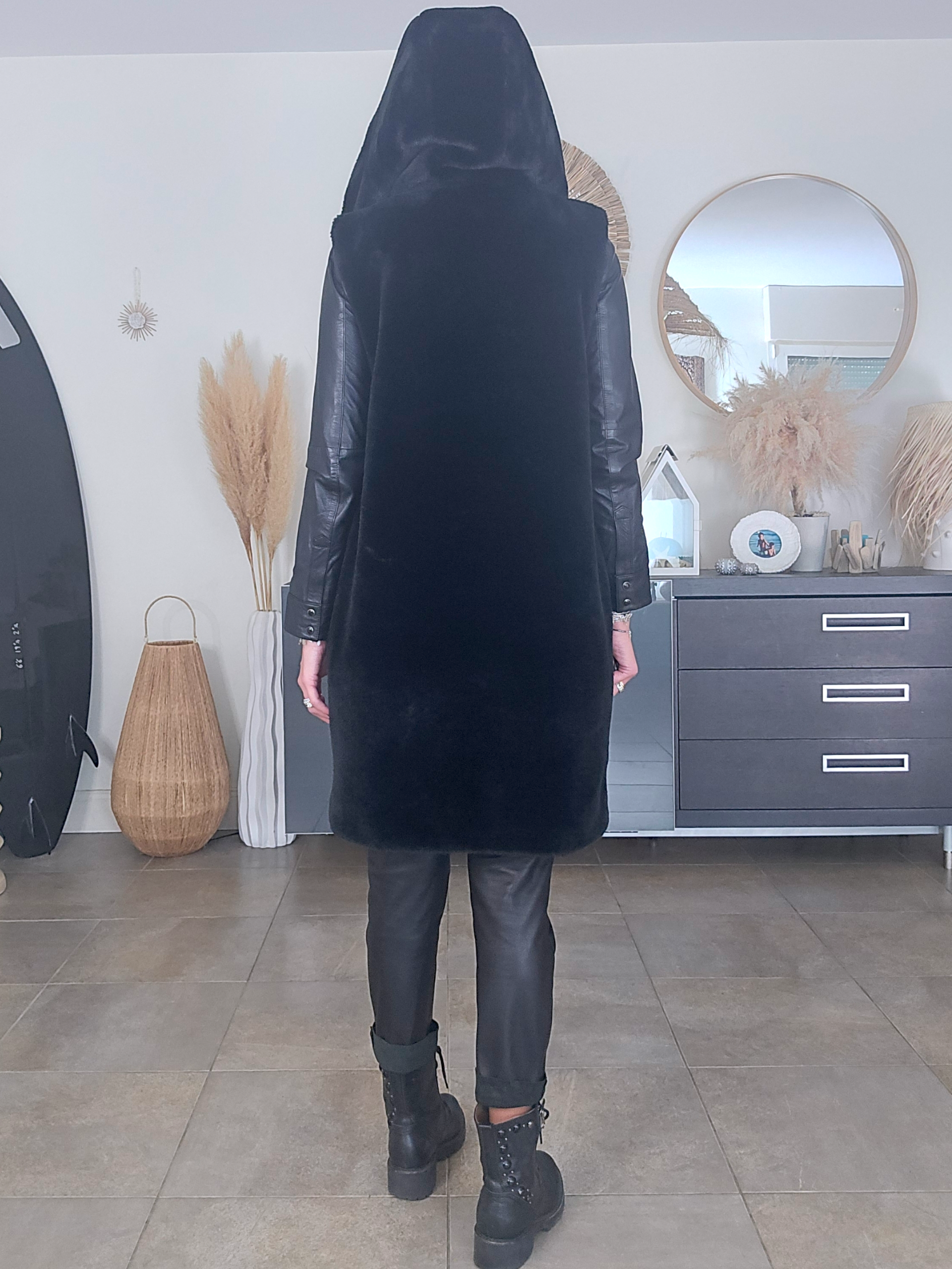 Manteau fausse fourrure noire à capuche sans manche.