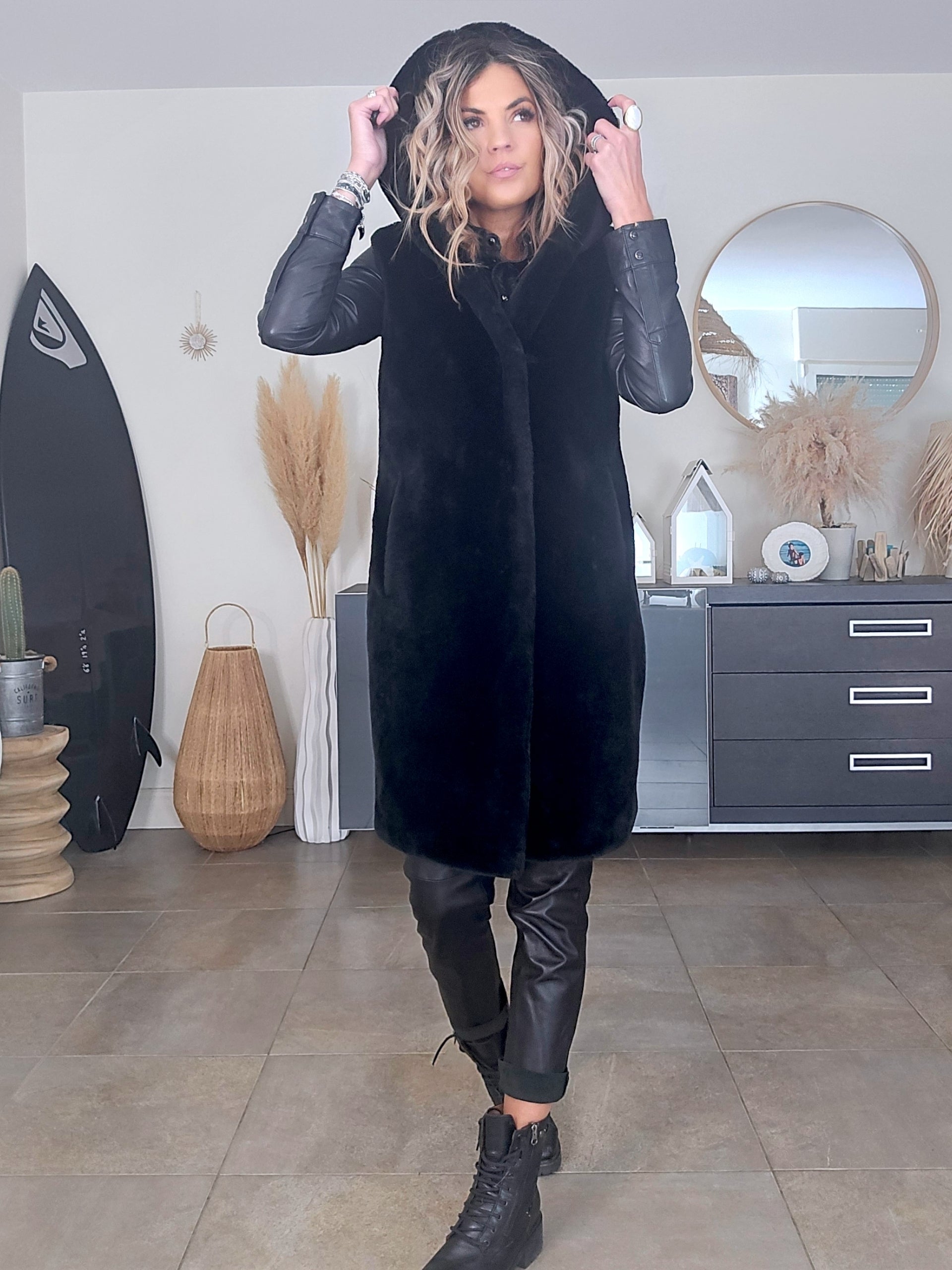 Manteau fausse fourrure noire à capuche sans manche.