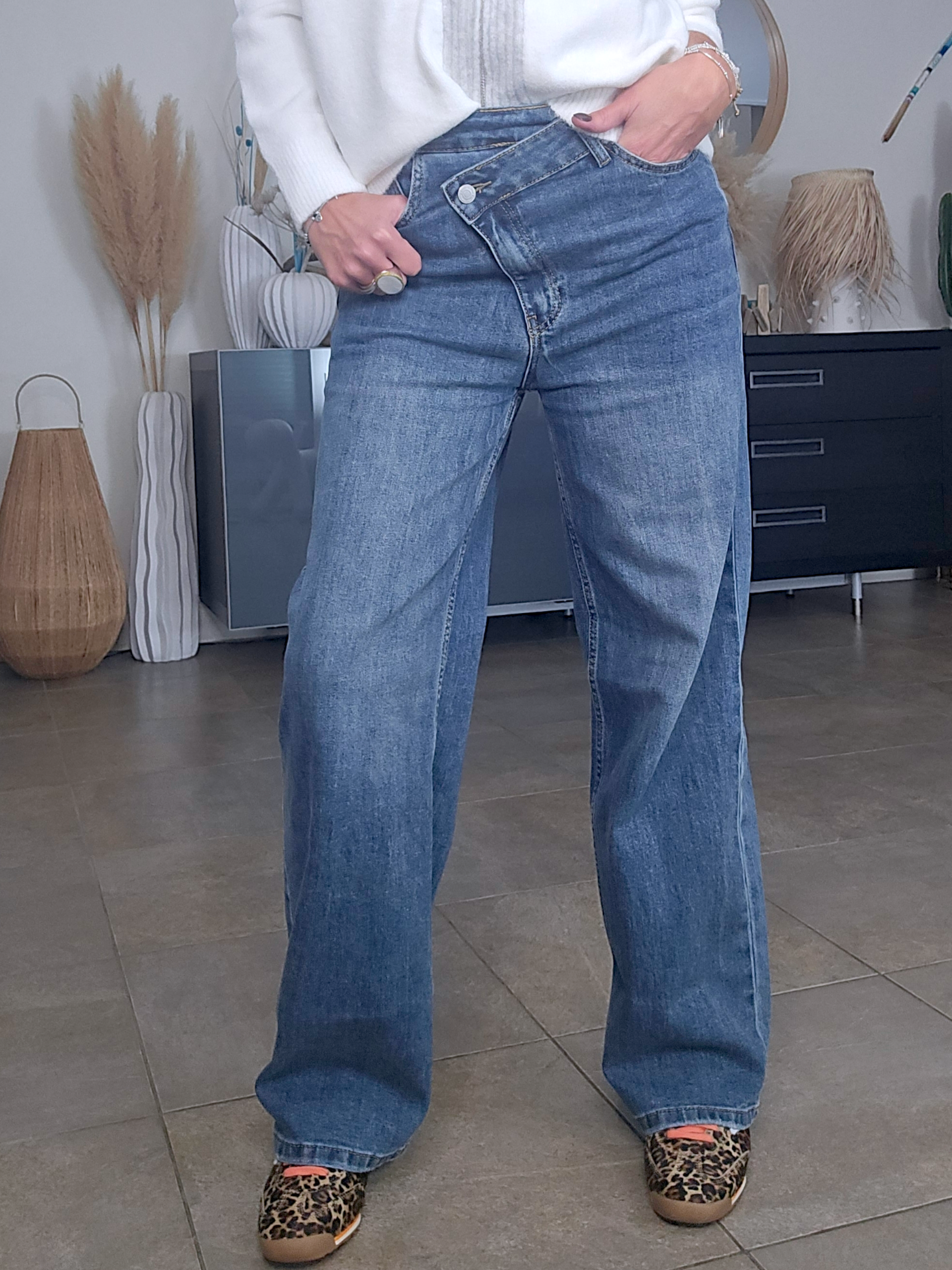 Jean bleu coupe droite à ceinture asymétrique.