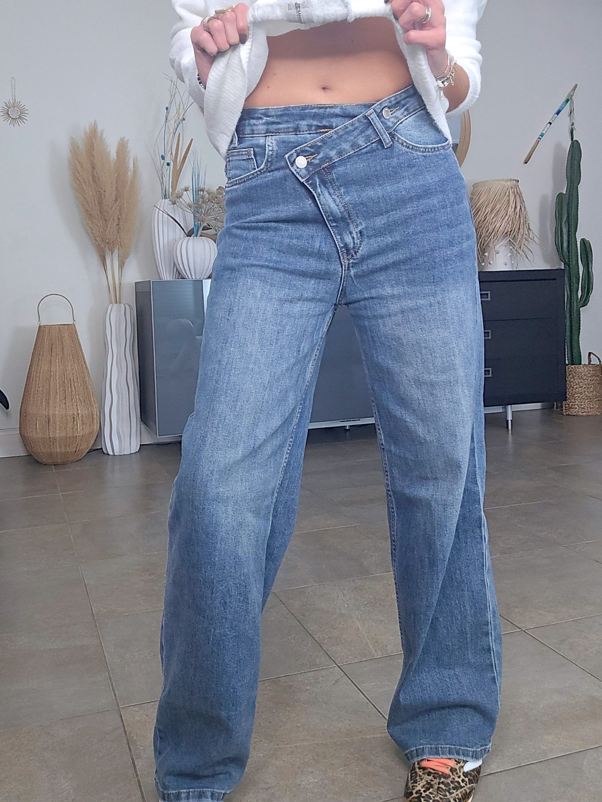 Jean bleu coupe droite à ceinture asymétrique.