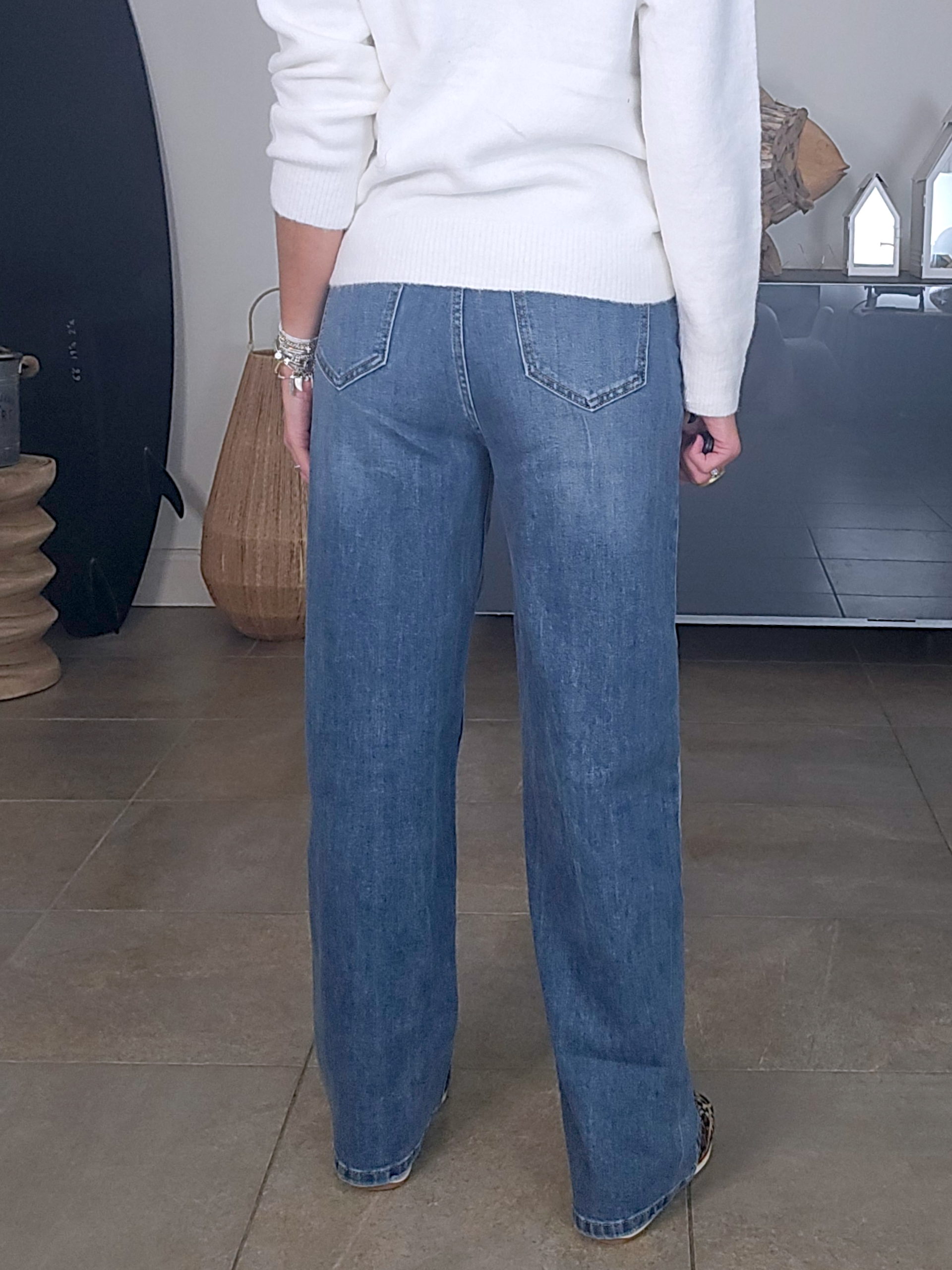 Jean bleu coupe droite à ceinture asymétrique.