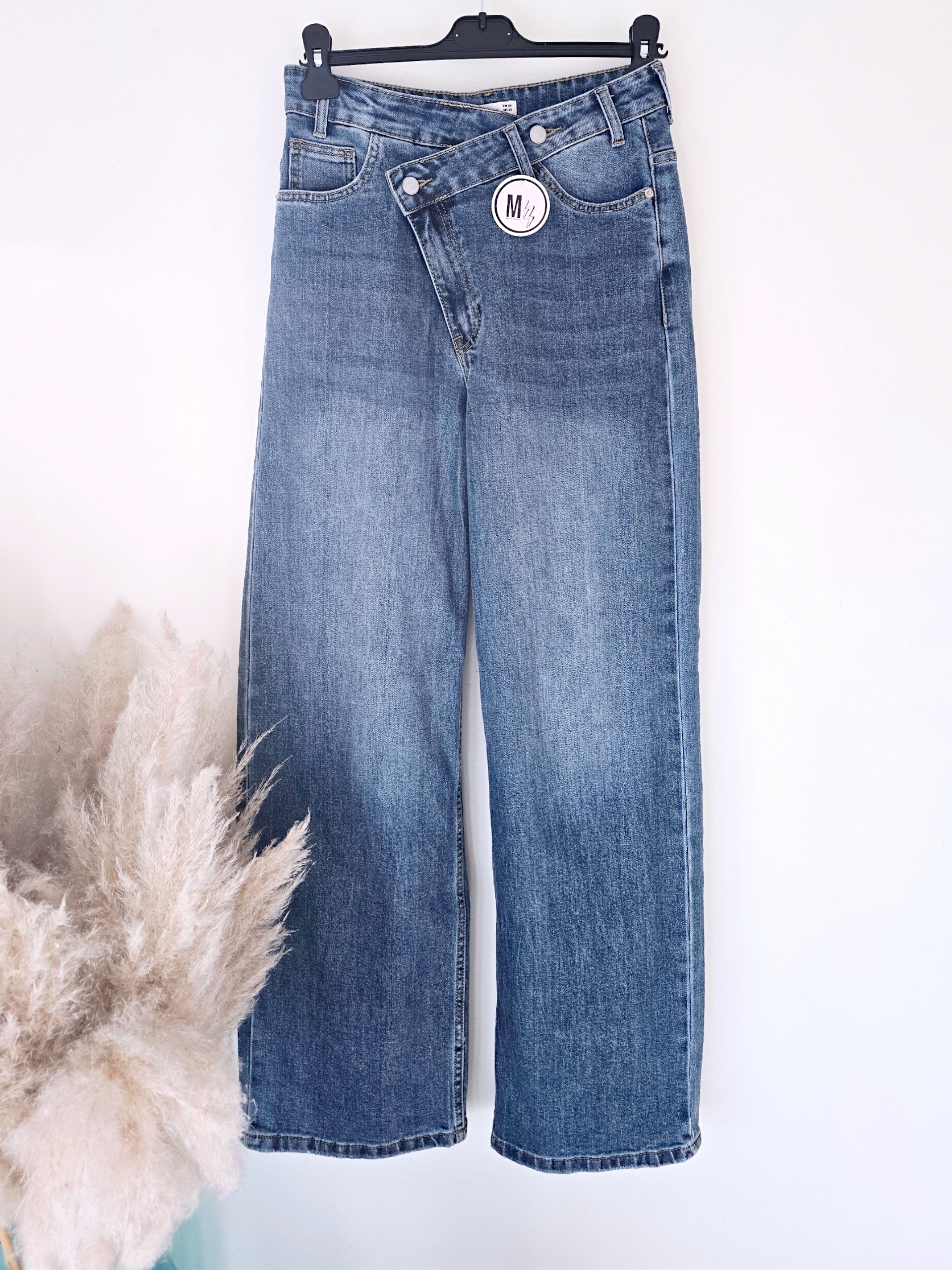 Jean bleu coupe droite à ceinture asymétrique.