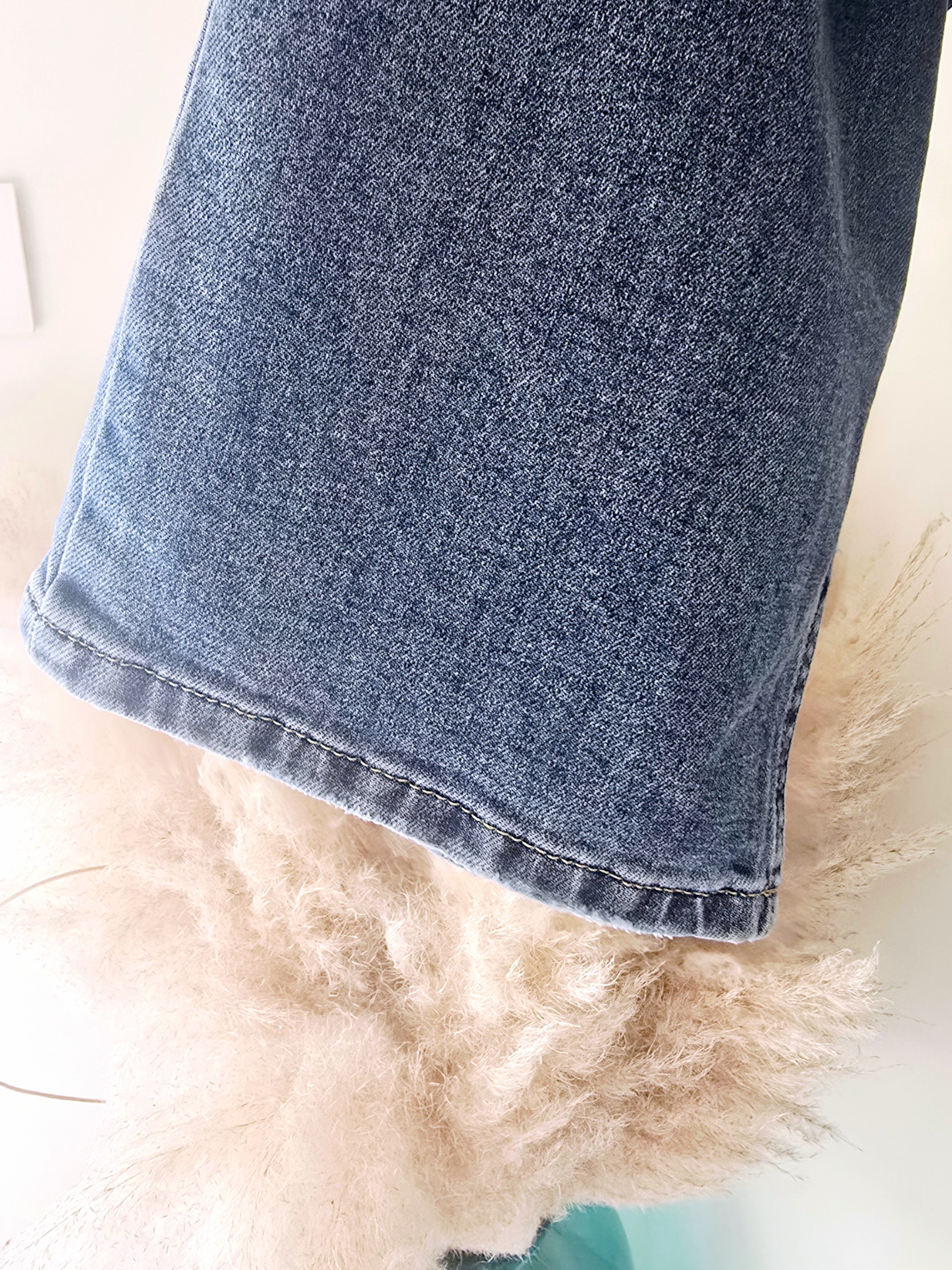 Jean bleu coupe droite à ceinture asymétrique.