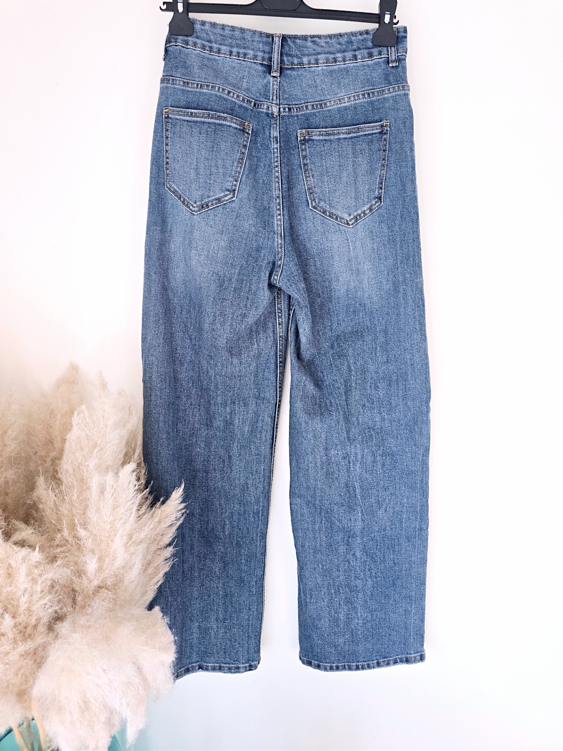 Jean bleu coupe droite à ceinture asymétrique.