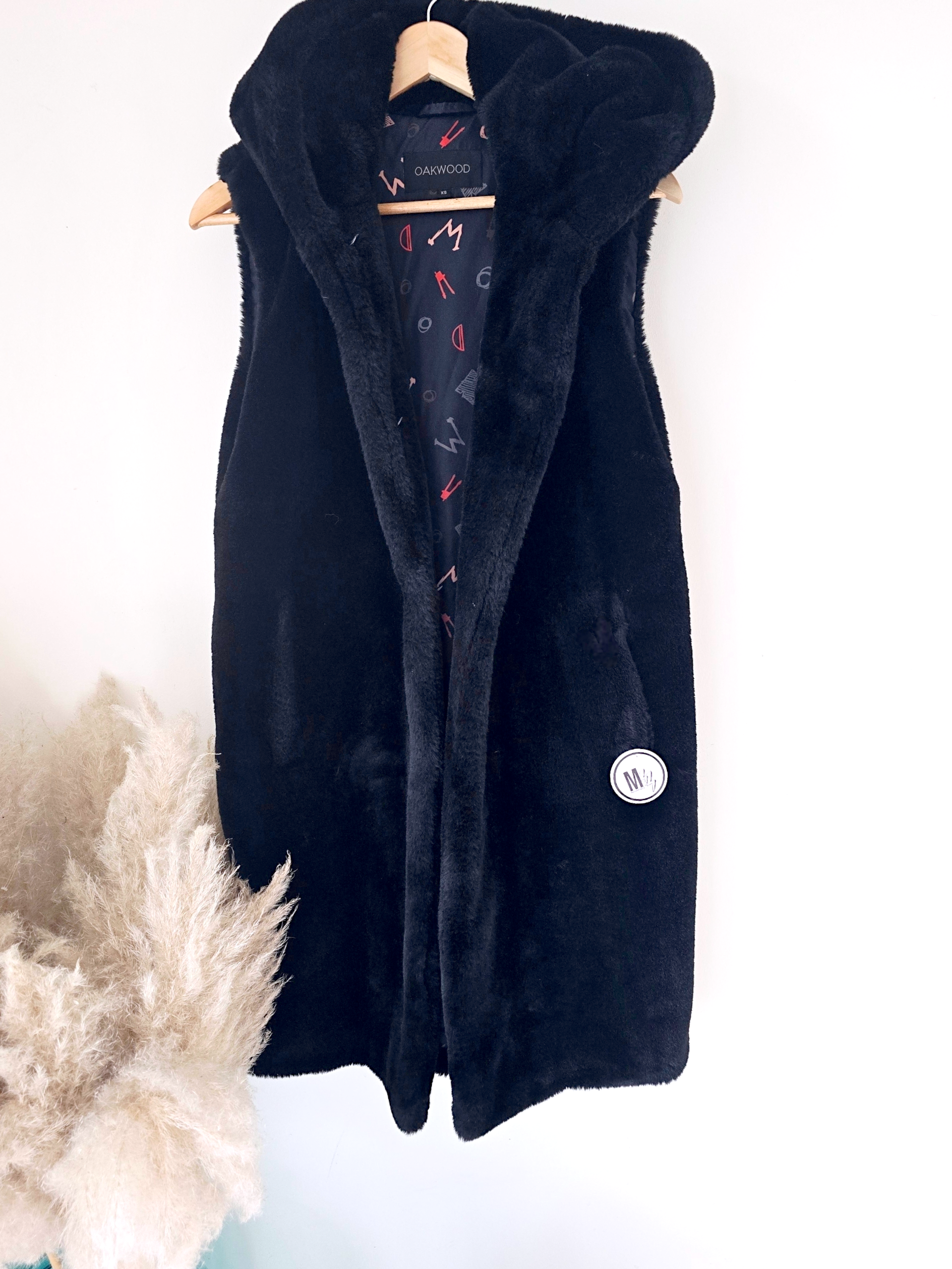 Manteau fausse fourrure noire à capuche sans manche.