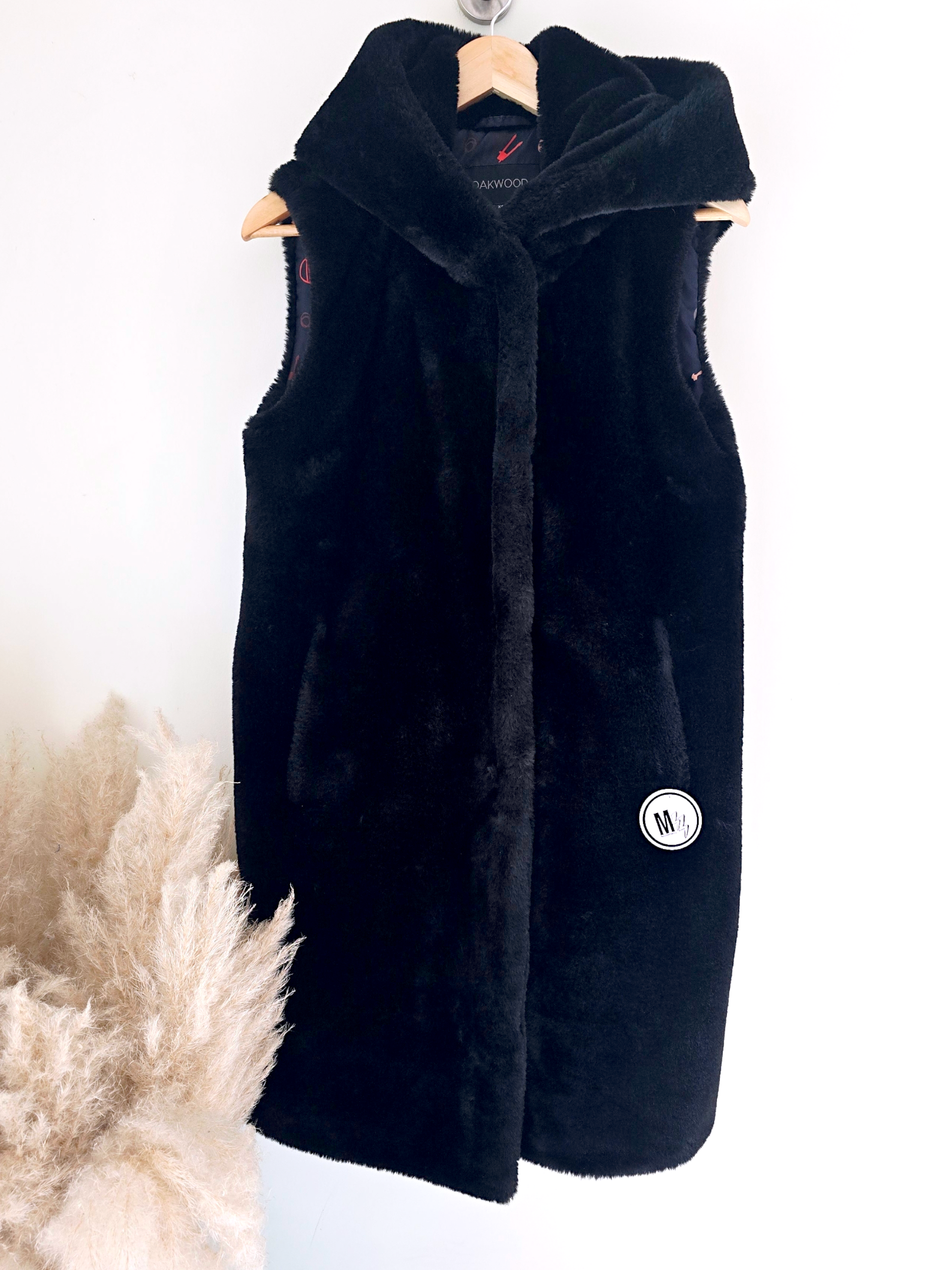 Manteau fausse fourrure noire à capuche sans manche.